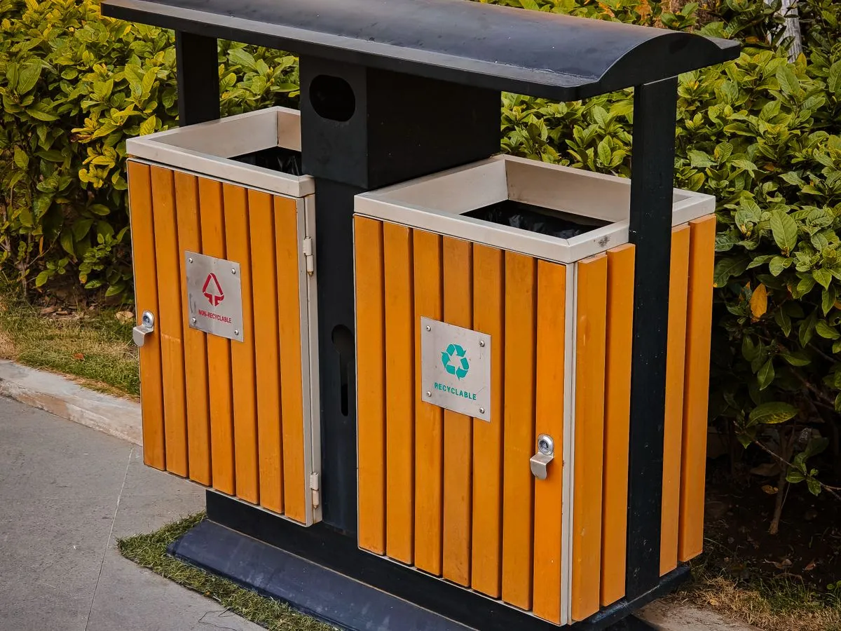 Basureros de reciclaje junto a un sendero con vegetación